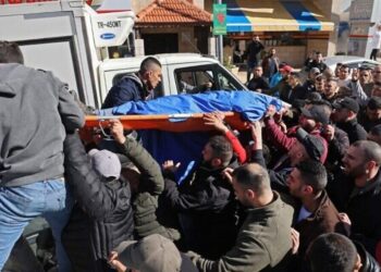 Palestinians carry the body of a man, one of three killed by Israeli froces in the occupied West Bank city of Nablus, on February 8, 2022. - Three Palestinians were killed by Israeli forces in the occupied West Bank city of Nablus today during what Israel described as an operation against a "terrorist cell". (Photo by JAAFAR ASHTIYEH / AFP)