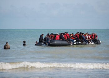 TOPSHOT - Migrants sit onboard an inflatable boat before attempting to illegally cross the English Channel to reach Britain, off the coast of Sangatte, northern France, on July 18, 2023. (Photo by BERNARD BARRON / AFP)