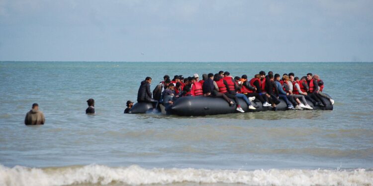 TOPSHOT - Migrants sit onboard an inflatable boat before attempting to illegally cross the English Channel to reach Britain, off the coast of Sangatte, northern France, on July 18, 2023. (Photo by BERNARD BARRON / AFP)