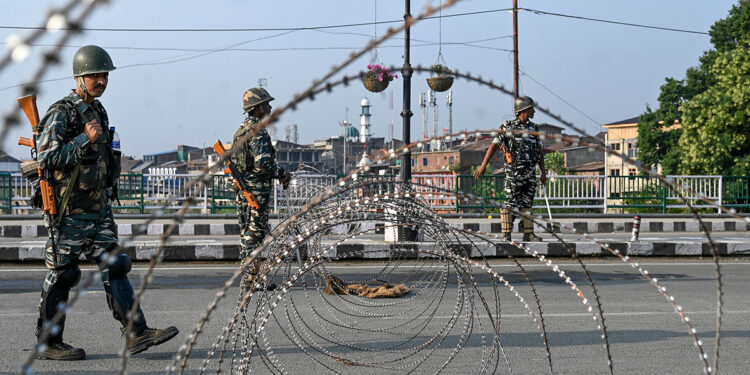 In this photo taken on August 5, 2019, Indian paramilitary troopers stand guard near a barbed fence wire as they block a road during a curfew in Srinagar. - India's home affairs minister on August 6 hailed "historic" legislation to bring Kashmir under its direct control, as New Delhi stepped up its clampdown on dissent in the restive Muslim-majority region. (Photo by TAUSEEF MUSTAFA / AFP)        (Photo credit should read TAUSEEF MUSTAFA/AFP/Getty Images)